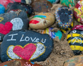 Bemalter Wanderstein mit Schriftzug am Strand