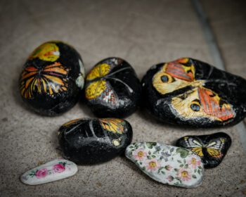 Mehrere Steine mit bunten Schmetterlings- und Blumenmotiven